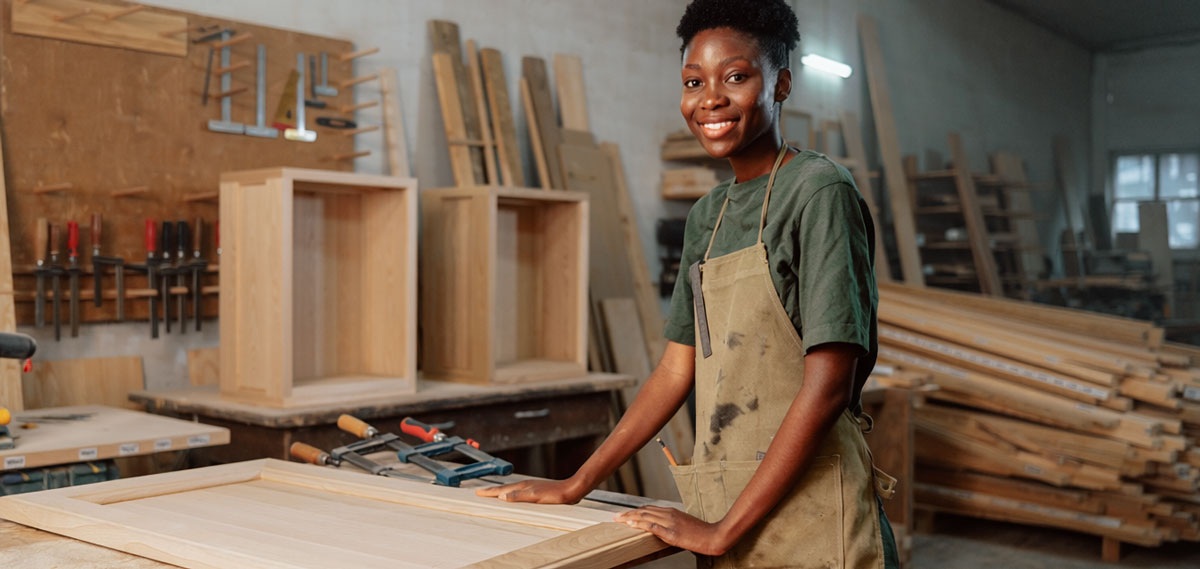 A woman standing in a wood cabinet shop.